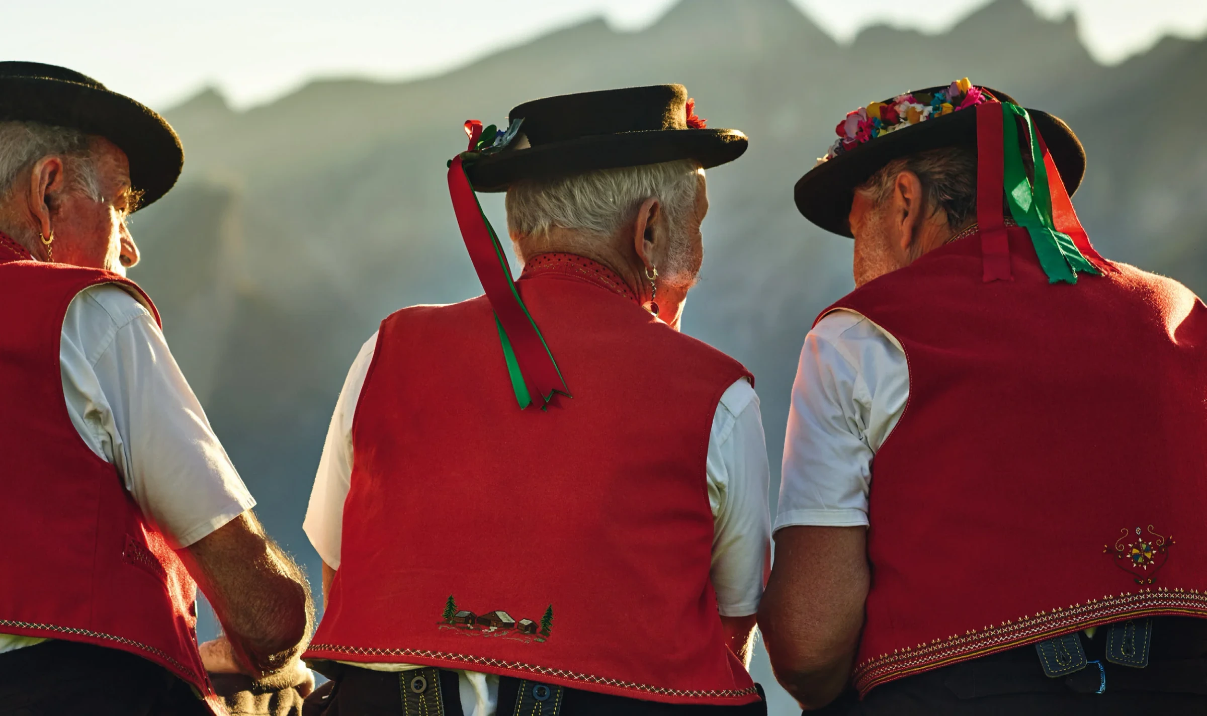Trois personnages de la campagne Appenzeller, vus de dos en costume traditionnel.