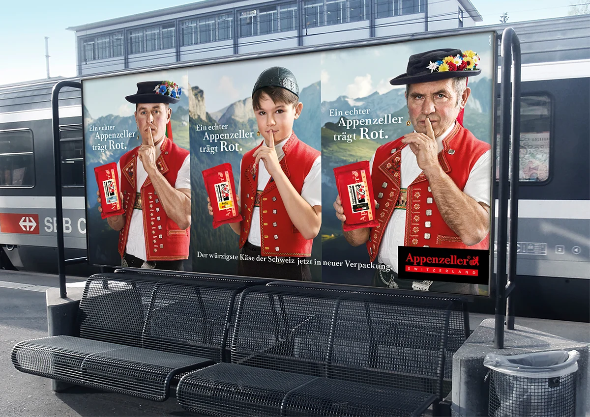 Affiche « Appenzeller trägt Rot » sur un quai de gare.