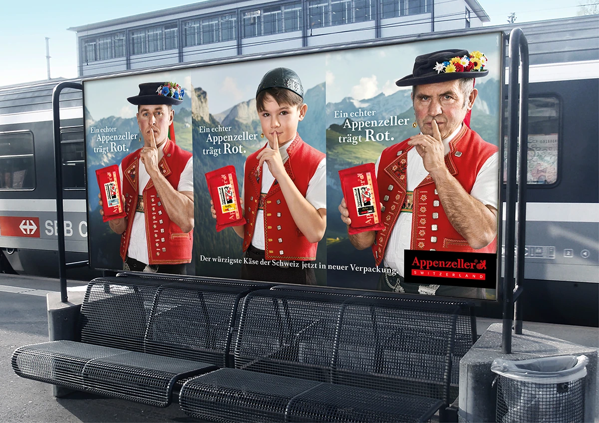 Affiche « Appenzeller trägt Rot » sur un quai de gare.