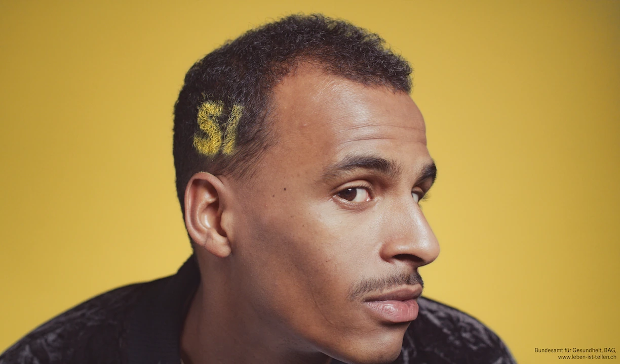 Portrait de campagne sur le don d’organes avec « Sì » dessiné dans les cheveux sur fond jaune.