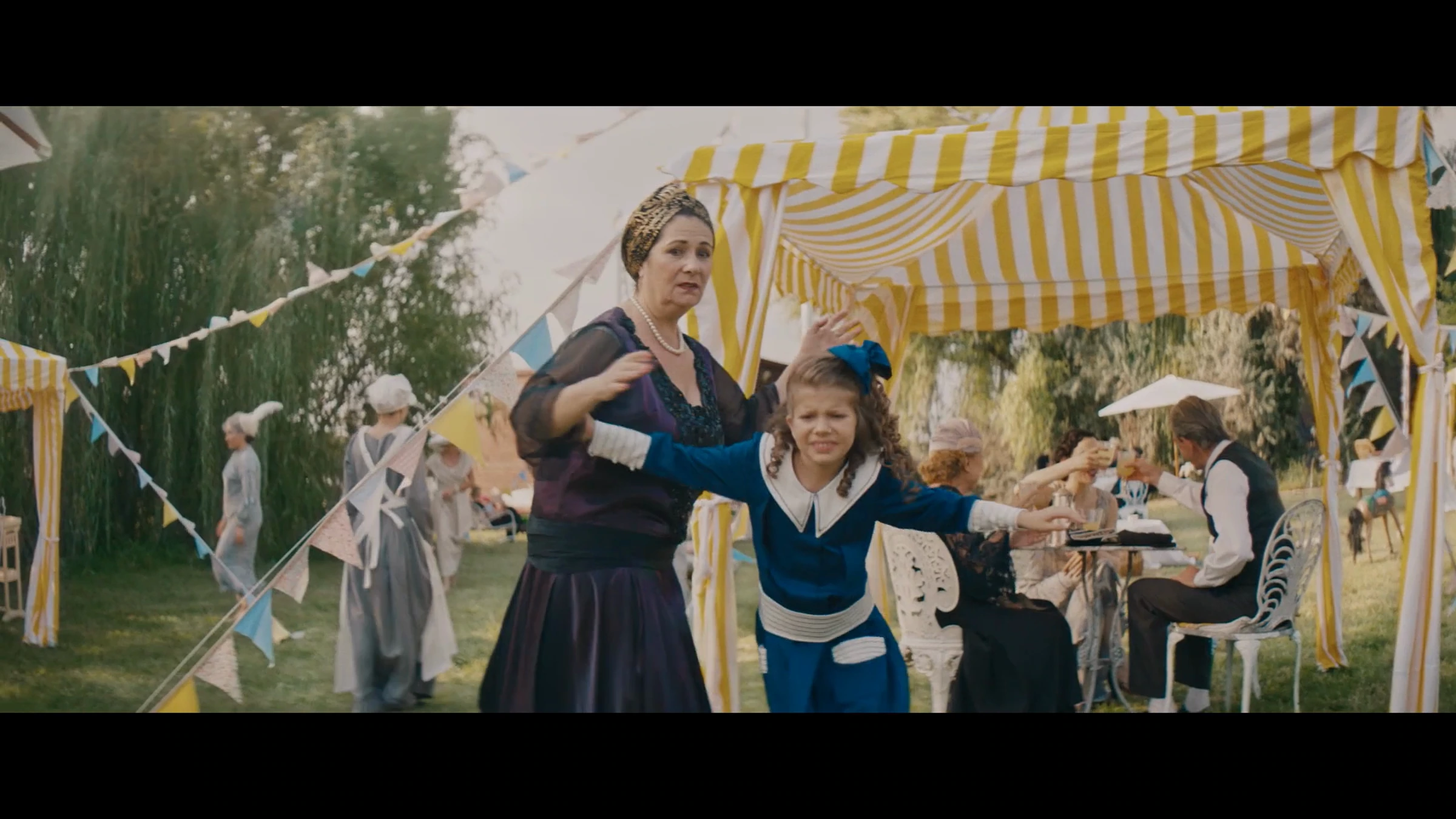 Film anniversaire Bell : une femme et une enfant devant un buffet de jardin.
