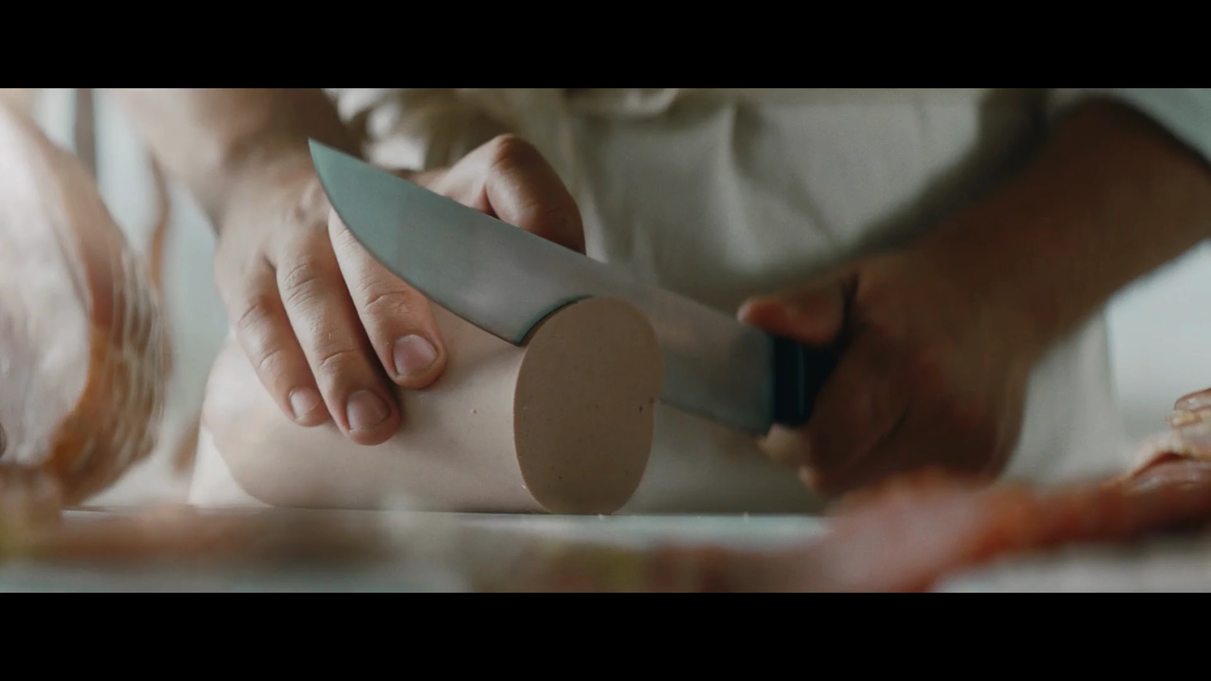 Film anniversaire Bell : découpe d’une saucisse en gros plan.
