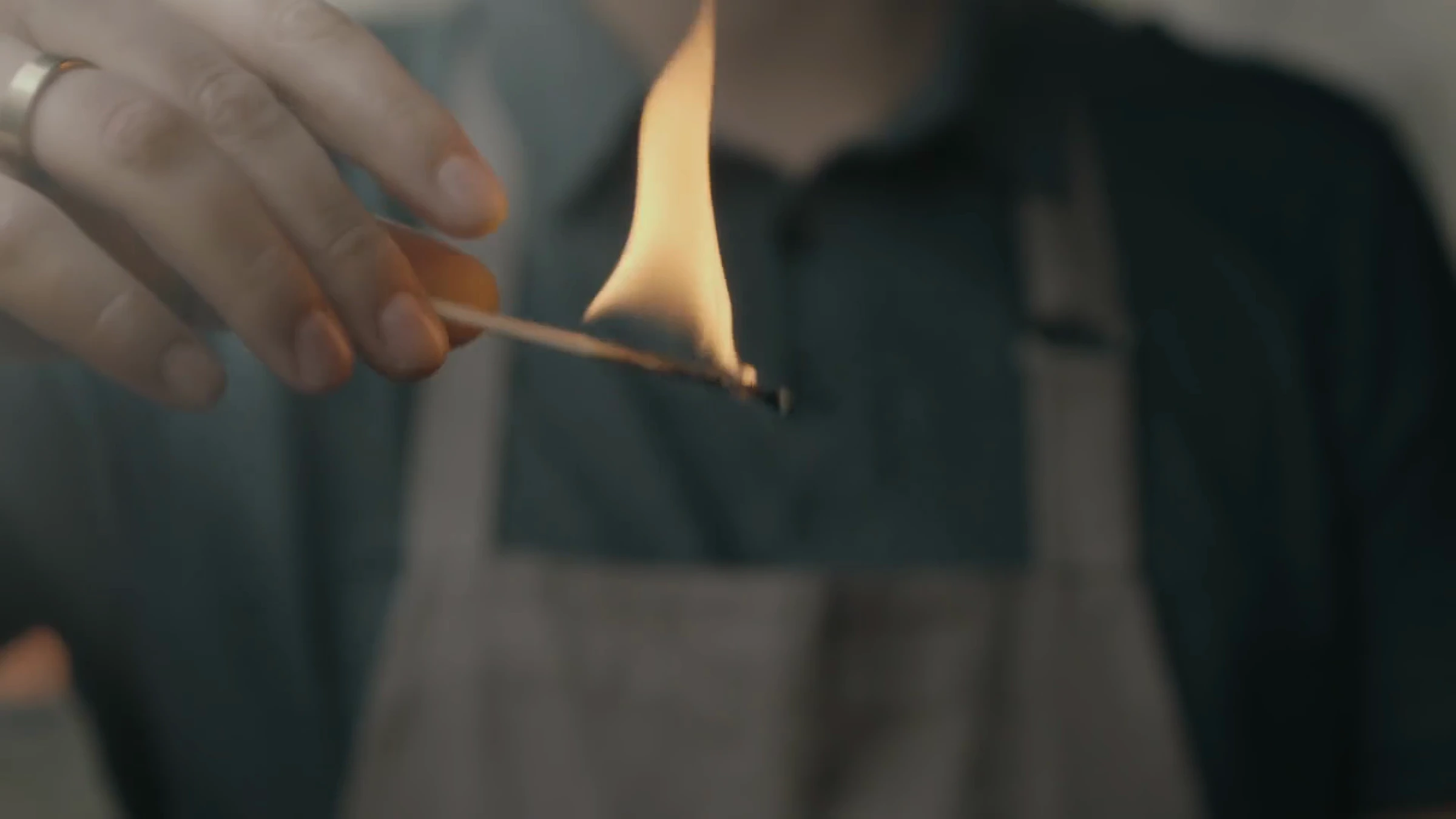 Film Bell BBQ : une main tient une allumette enflammée.