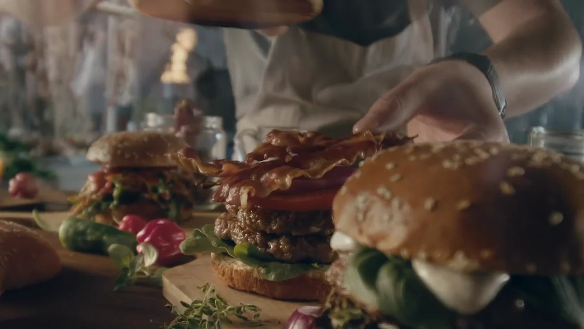 Film Bell BBQ : préparation de plusieurs burgers en gros plan.