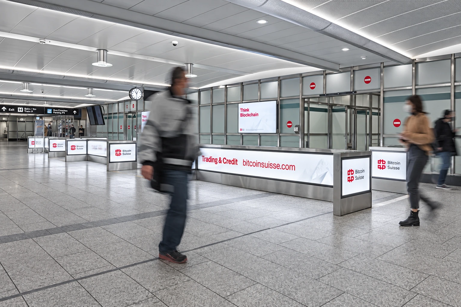 Habillage Bitcoin Suisse des portiques et panneaux lumineux d’un aéroport.
