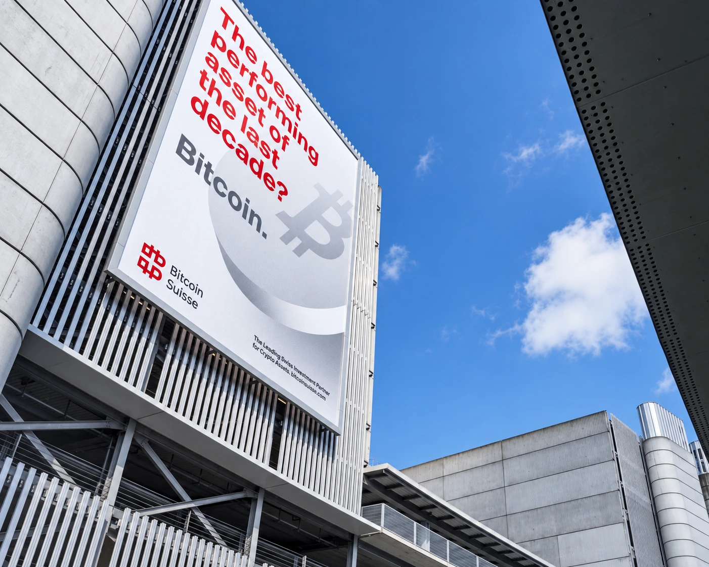 Grande affiche Bitcoin Suisse sur une façade d’aéroport.