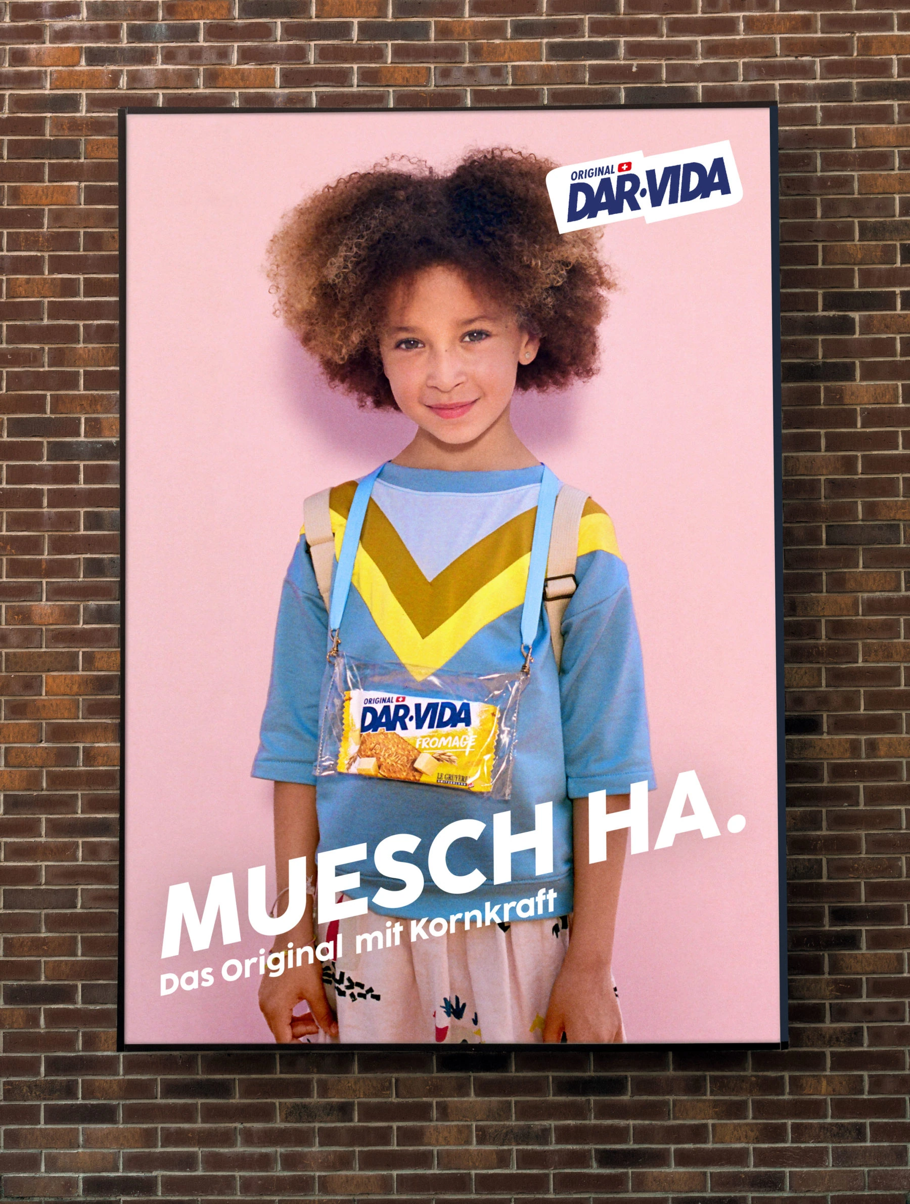 Affiche DAR-VIDA avec une enfant sur fond rose, installée sur un mur de briques.