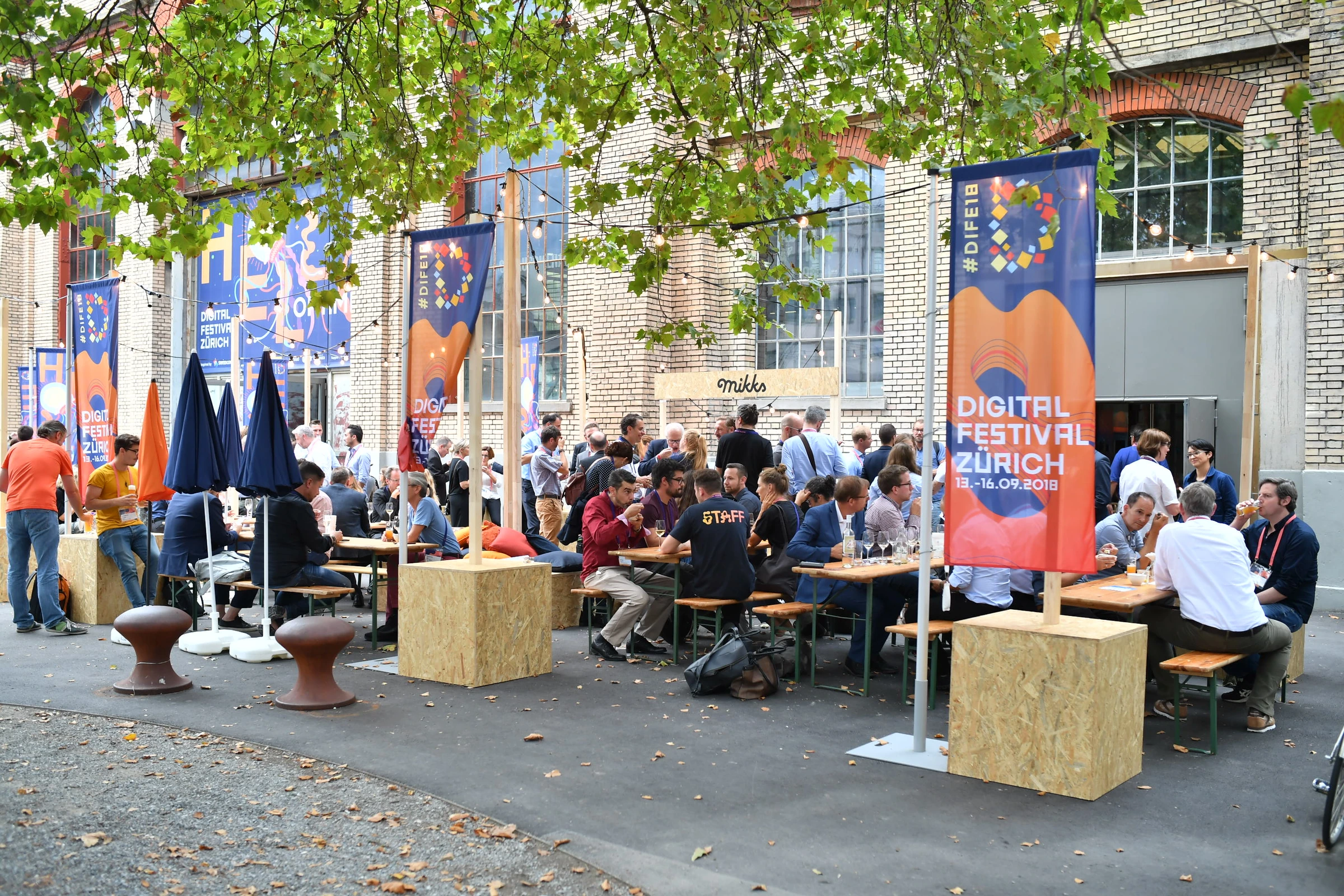 Terrasse du Digital Festival avec drapeaux illustrés et participants.