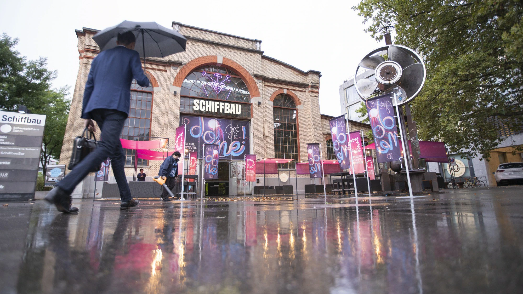 Entrée du Schiffbau sous la pluie, habillée aux couleurs « Get it done ».