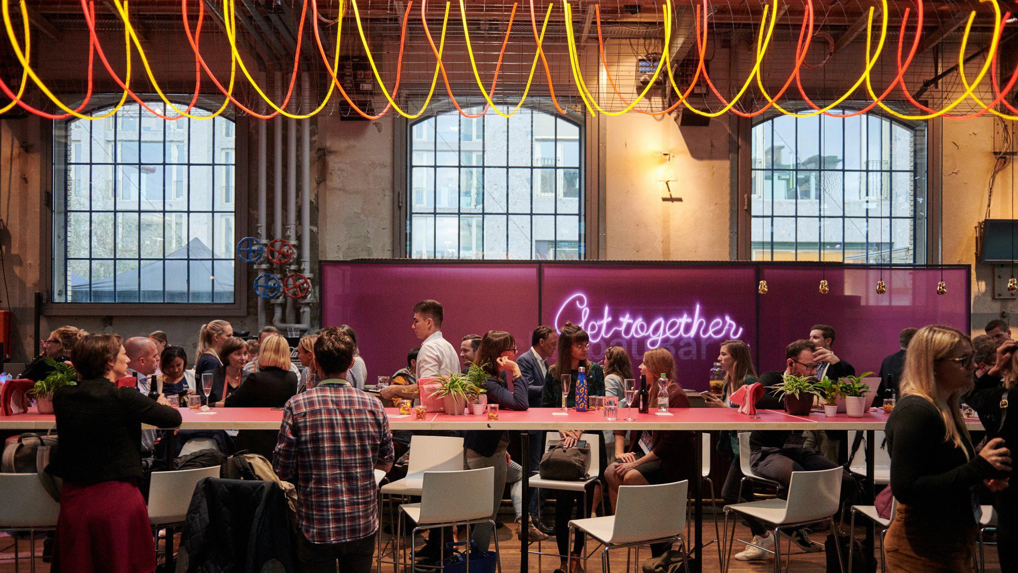 Espace repas du Digital Festival sous des suspensions orange et l’inscription « Get together ».