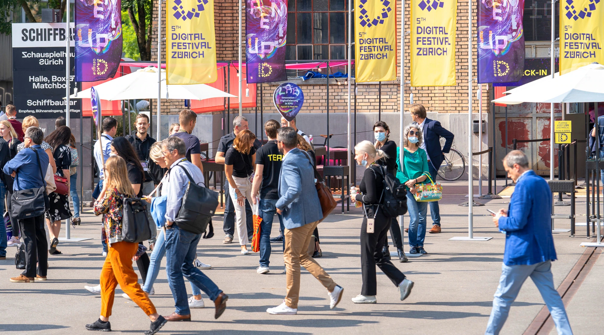Participants devant les drapeaux violets et jaunes « Open Up! ».
