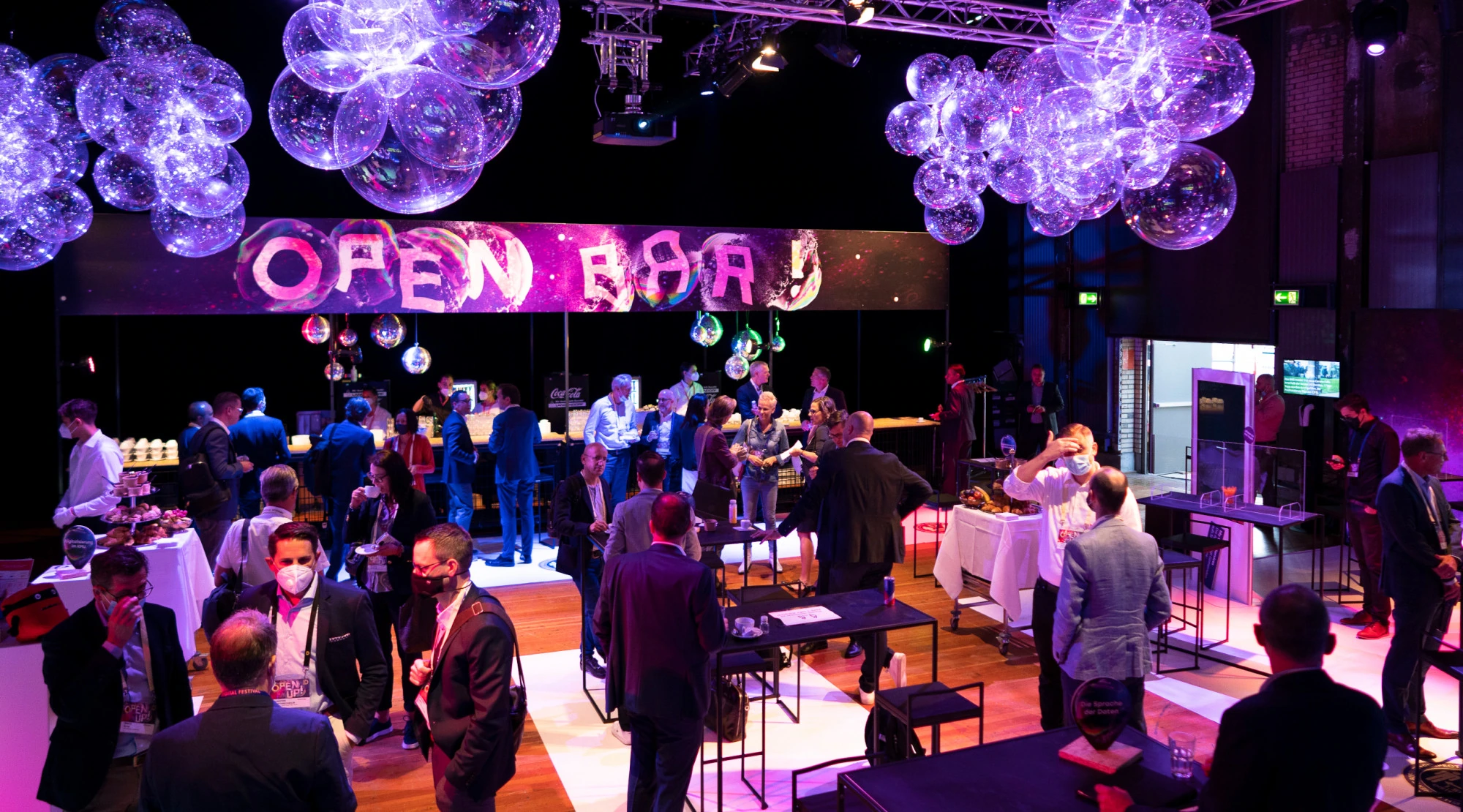 Espace « Open Bar » du Digital Festival sous des sphères lumineuses violettes.