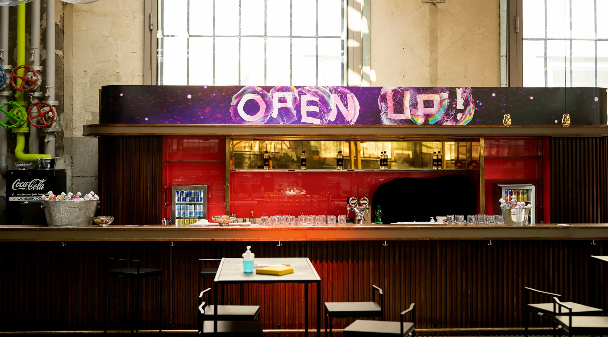 Comptoir dans la halle du festival sous une enseigne « Open Up! ».