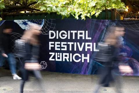 Bâche extérieure du Digital Festival Zürich devant des passants en mouvement.