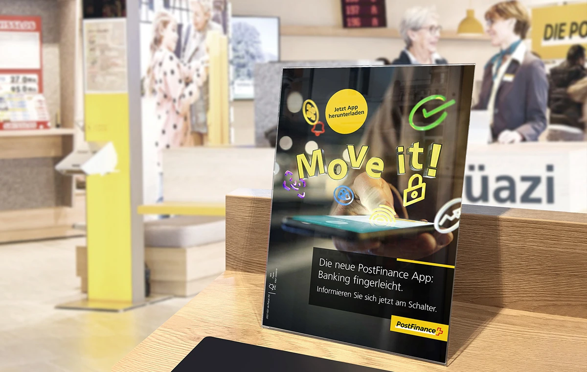 Présentoir PostFinance « Move it! » installé sur un comptoir.