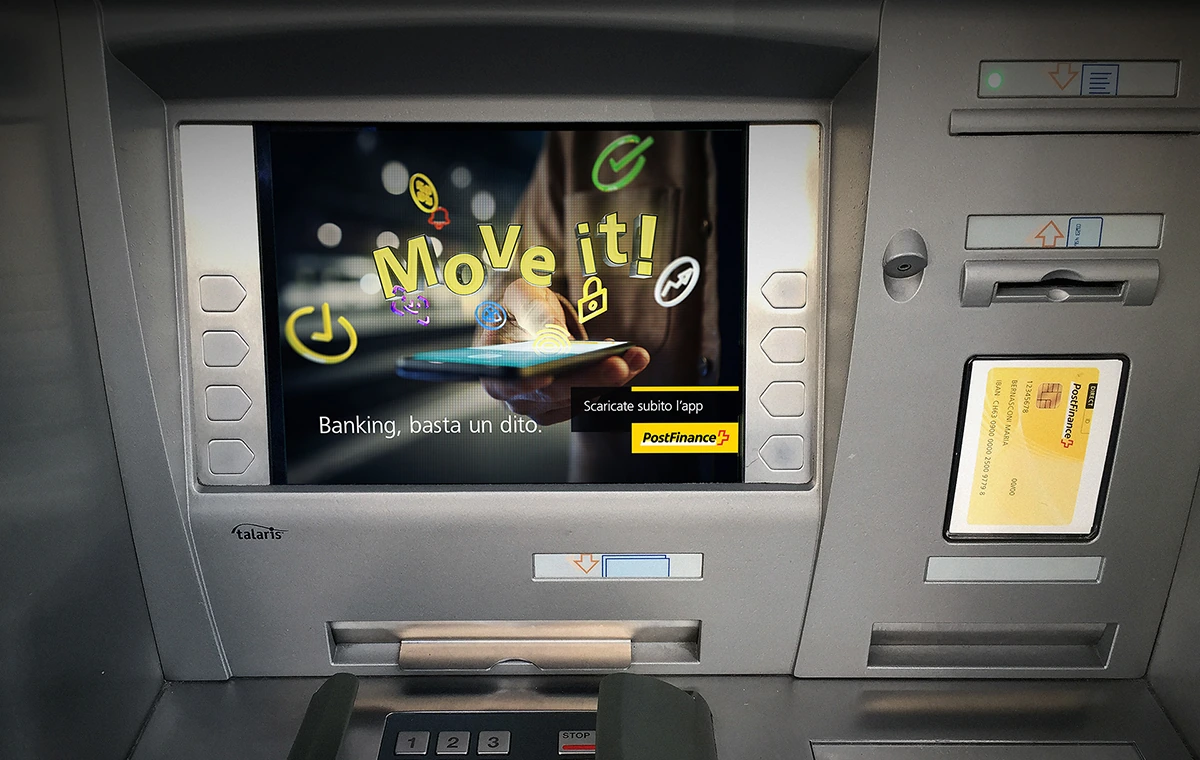 Campagne PostFinance « Move it! » affichée sur l’écran d’un distributeur.