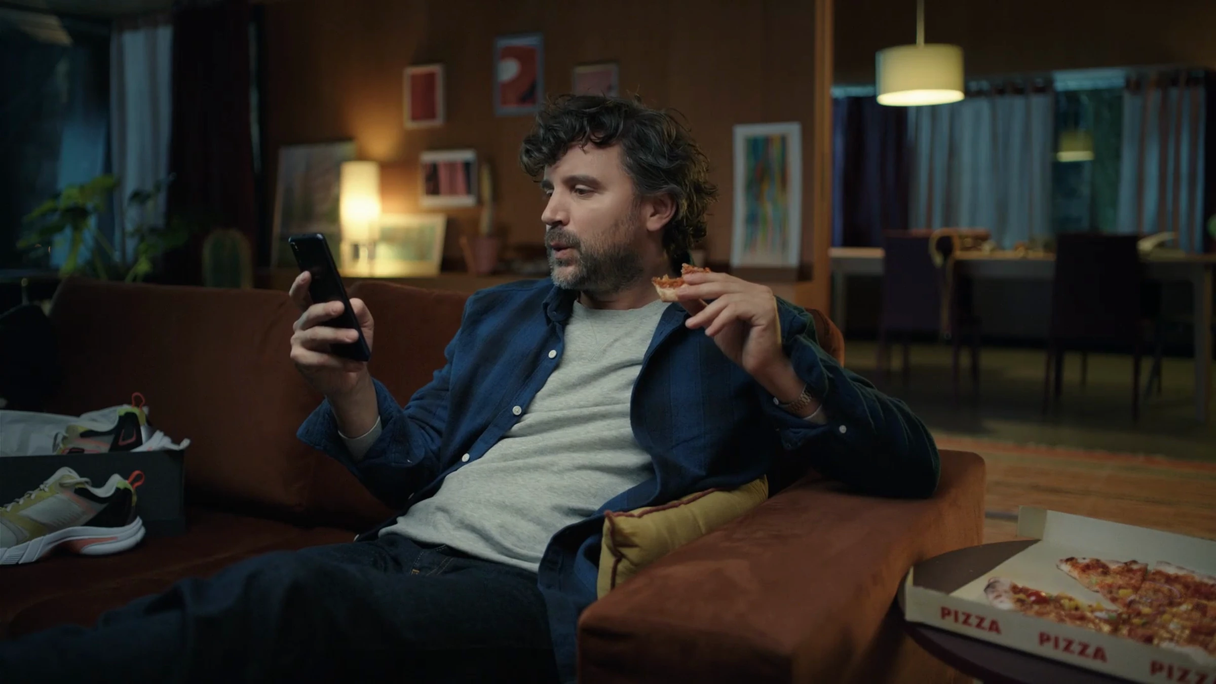 Image du film PostFinance : un homme consulte son téléphone dans un fauteuil.