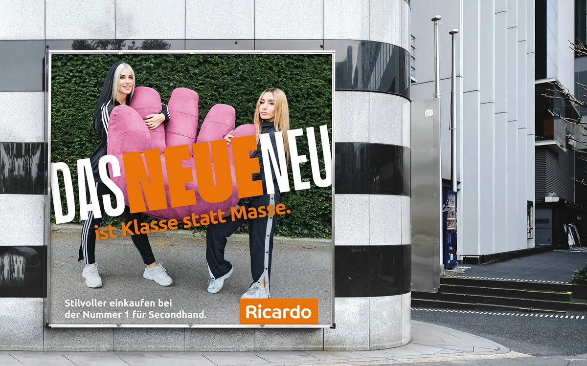 Affiche Ricardo avec deux femmes portant un fauteuil rose en forme de main.