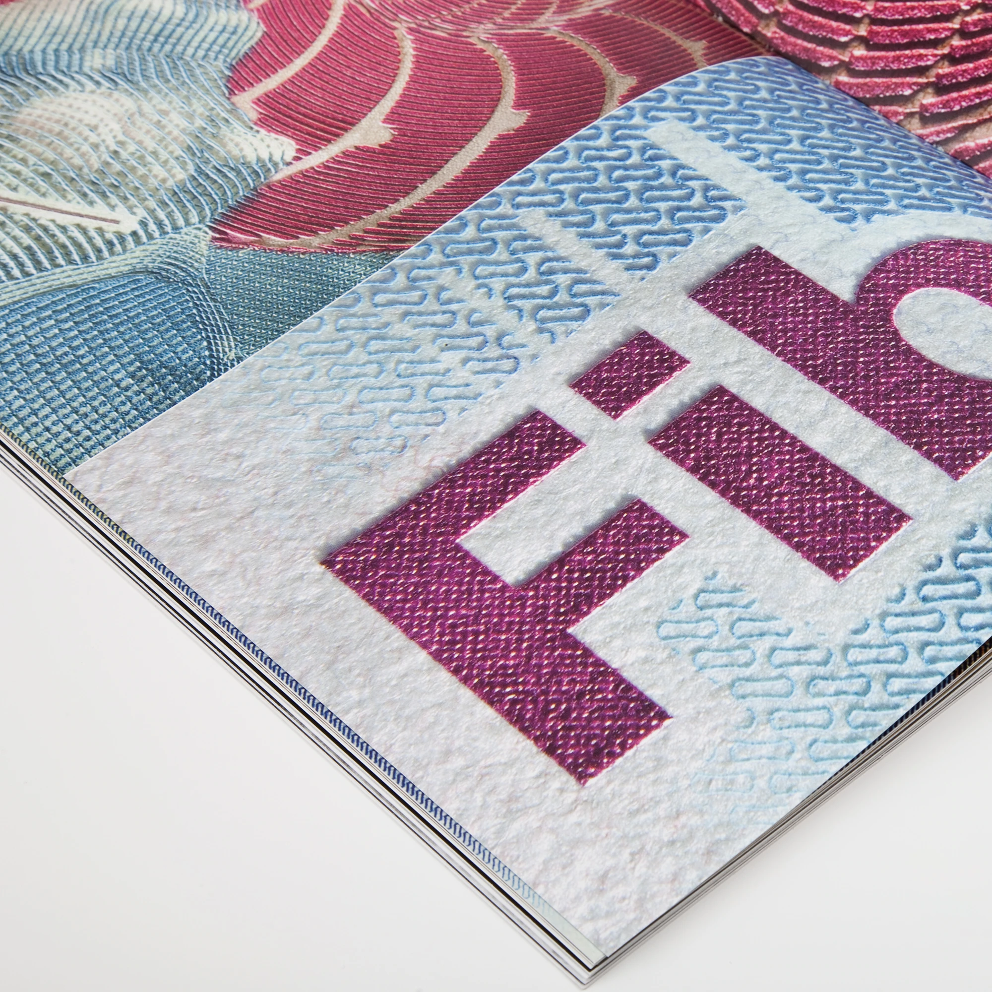Gros plan d’une couverture SICPA avec texture de billet et lettres magenta.