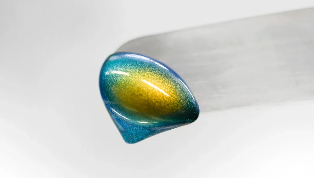 Goutte de matière irisée bleue et dorée dans l’univers visuel SICPA.