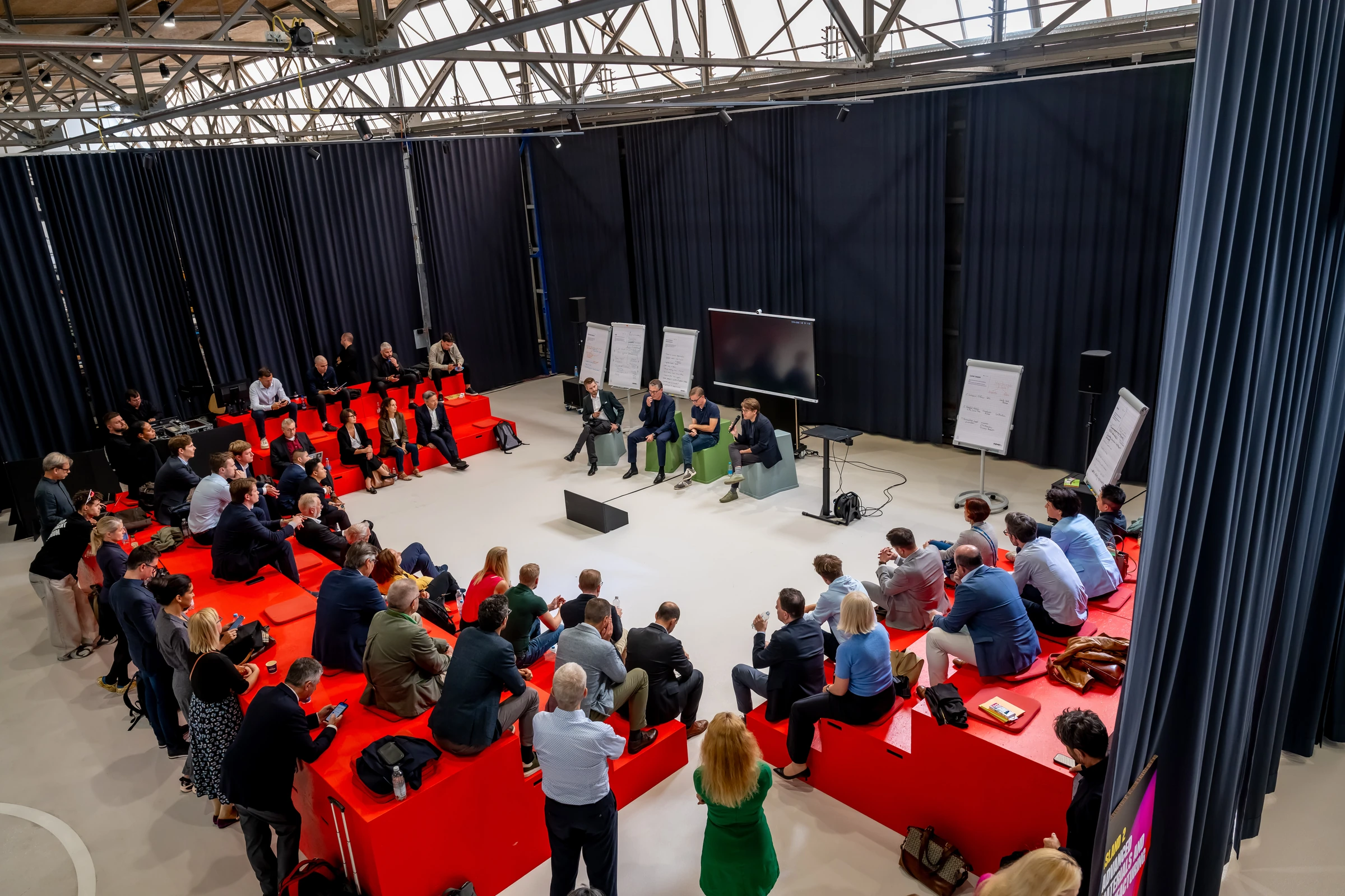 Vue d’ensemble d’un atelier du forum, organisé autour de gradins rouges.