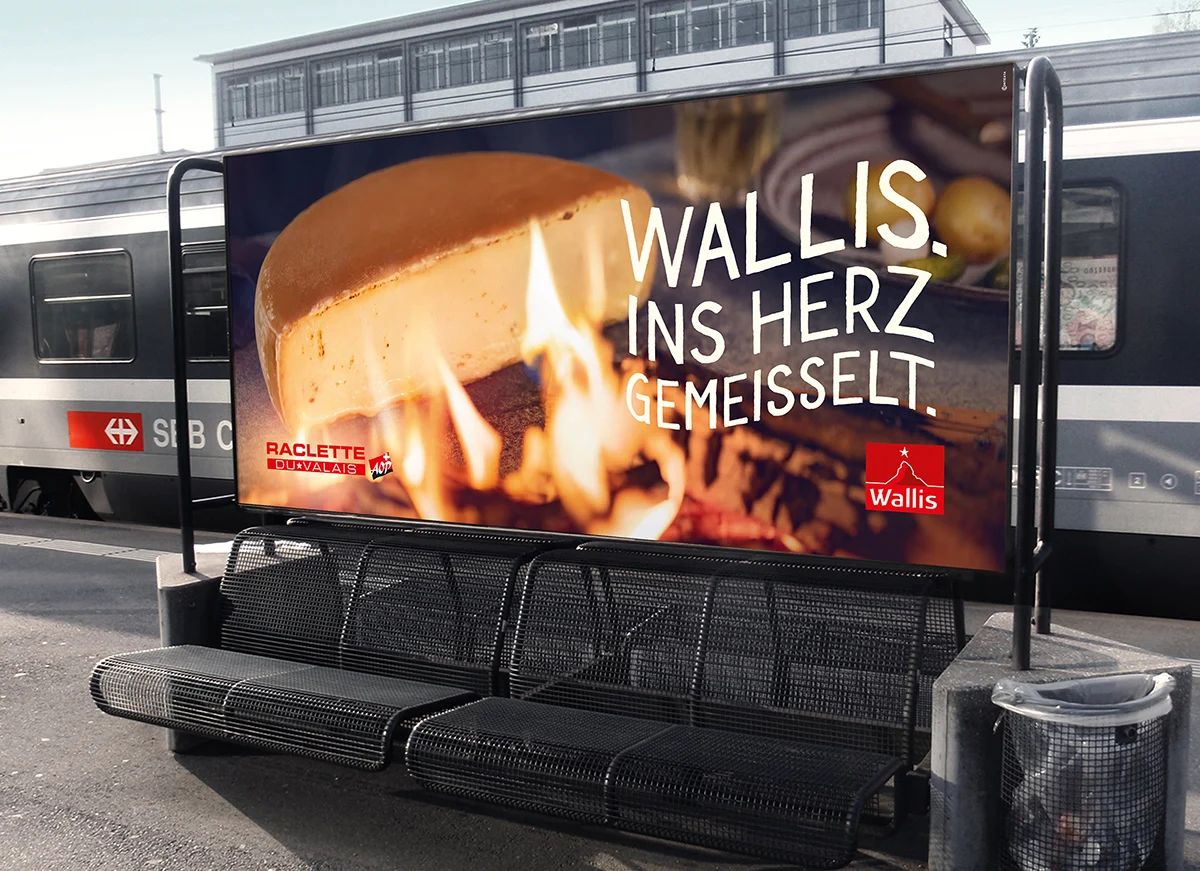 Affiche Valais / Wallis présentant une raclette sur un quai de gare.